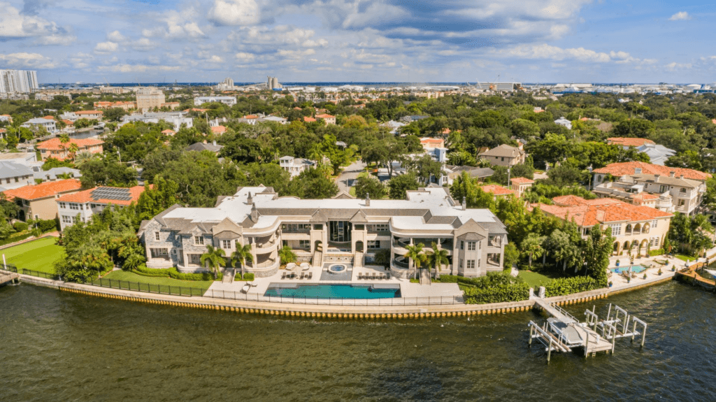 Aerial photograph of a waterfront estate with a pool and dock on Tampa Bay, with the Tampa skyline visible in the distance
